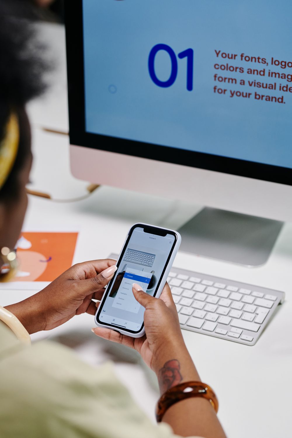 A person using a mobile phone alongside a desktop computer